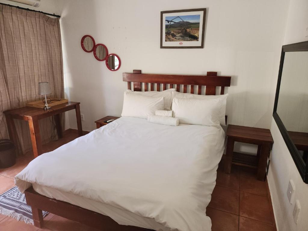 um quarto com uma cama com lençóis brancos e almofadas em Sirwine Hotel, Bar and Restuarant em Windhoek
