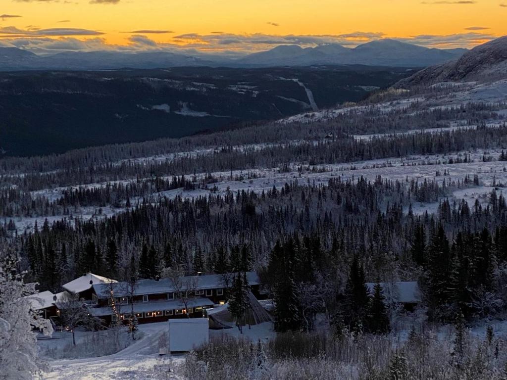 a train on a snowy mountain with a sunset in the background at Buustamons Fjällgård in Åre