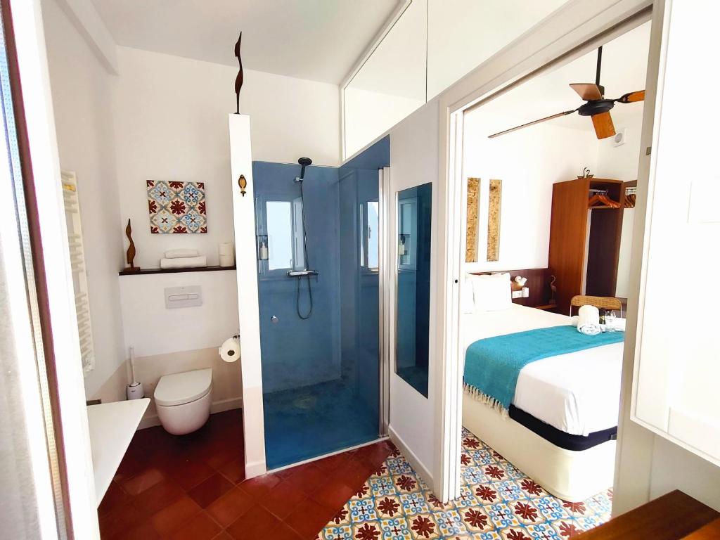 a bedroom with a bed and a bathroom with a shower at Vejerísimo Casa Boutique in Vejer de la Frontera