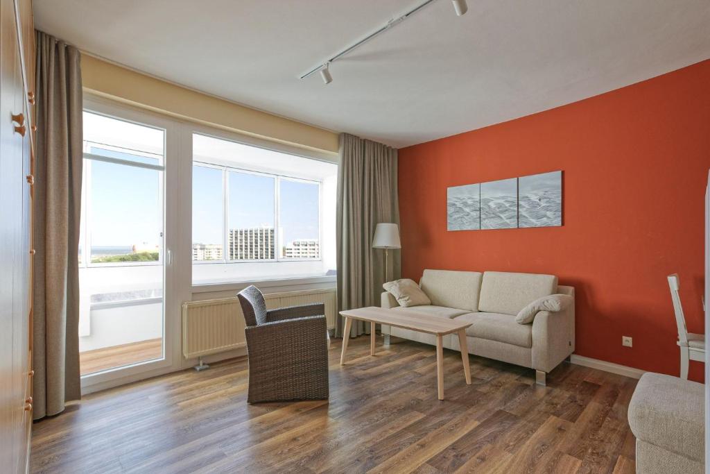 uma sala de estar com paredes cor de laranja e um sofá em Haus Atlantic, FeWo 513 em Döse