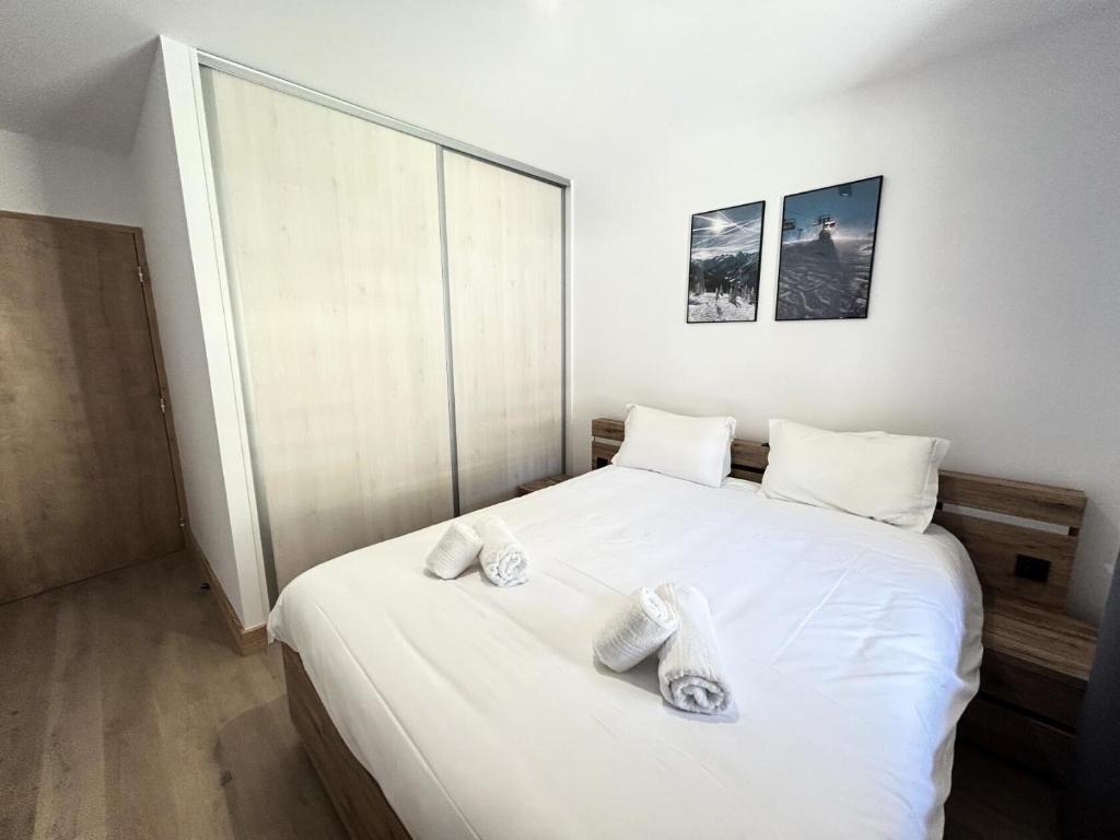 a bedroom with a white bed with towels on it at Résidence LES TERRASSES DE LA VANOISE - Appartement LES TERRASSES DE LA VAN 924 in Champagny-en-Vanoise