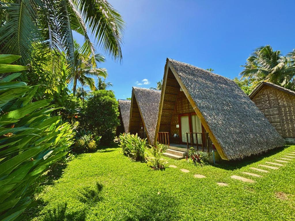 a house with a thatched roof and a yard at Triangle Palms Siargao in General Luna