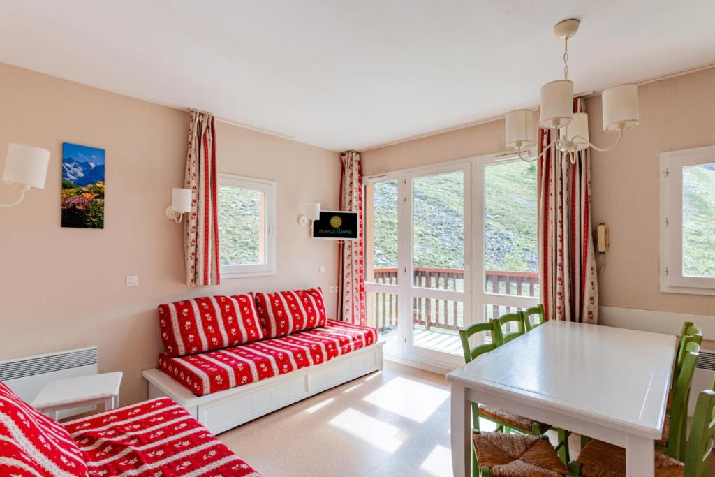 uma sala de estar com um sofá vermelho e uma mesa em Résidence Le Thabor - maeva Home - Appartement 3 pièces 6 personnes - Conf 734 em Le Désert
