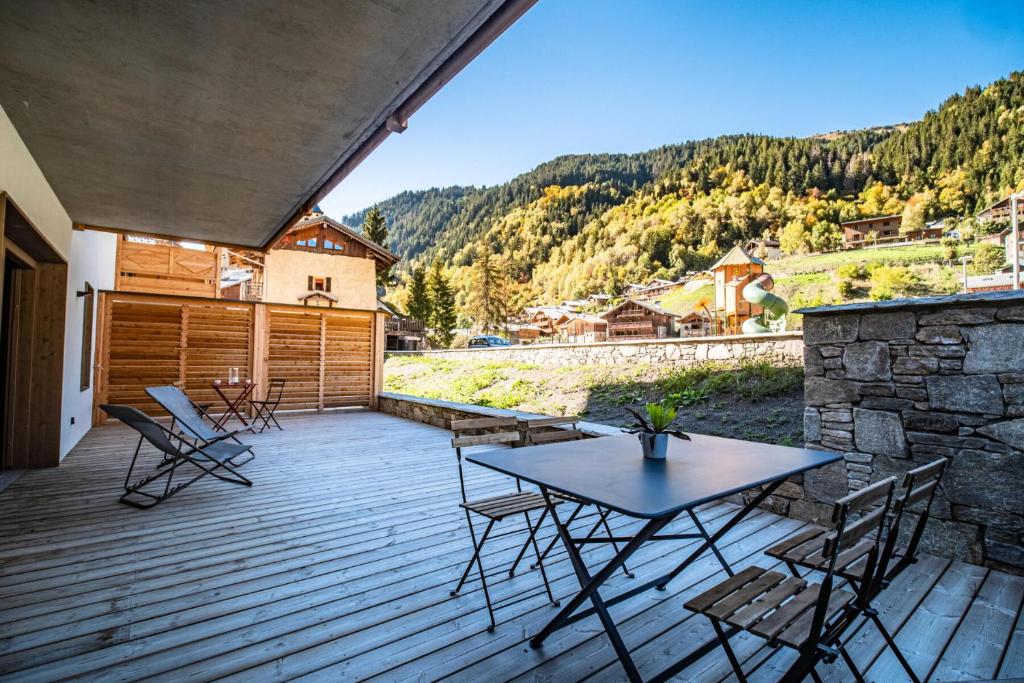 a wooden deck with a table and chairs on it at Résidence LES TERRASSES DE LA VANOISE - Appartement EXCLUSIF ! LES TERRASSE 974 in Champagny-en-Vanoise