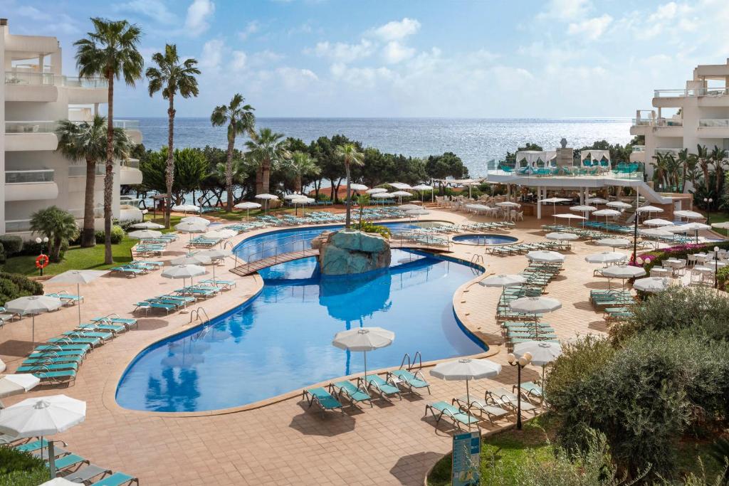 an overhead view of a resort pool with chairs and umbrellas at Aparthotel Tropic Garden in Santa Eularia des Riu