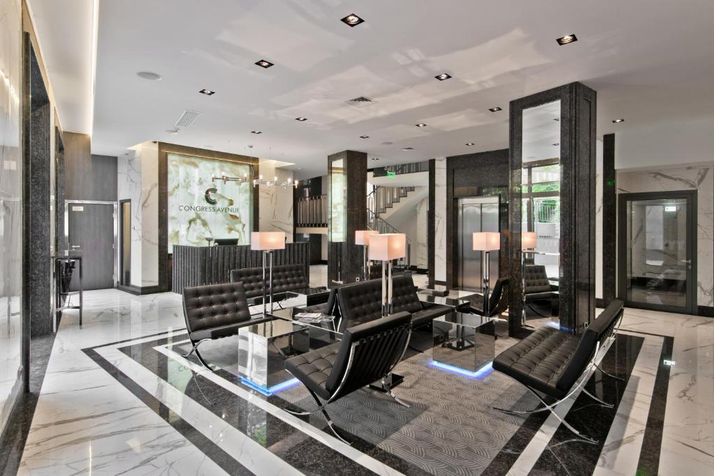 Congress Avenue Hotel في فيلنيوس: لوبي وكراسي سوداء وطاولة زجاجية