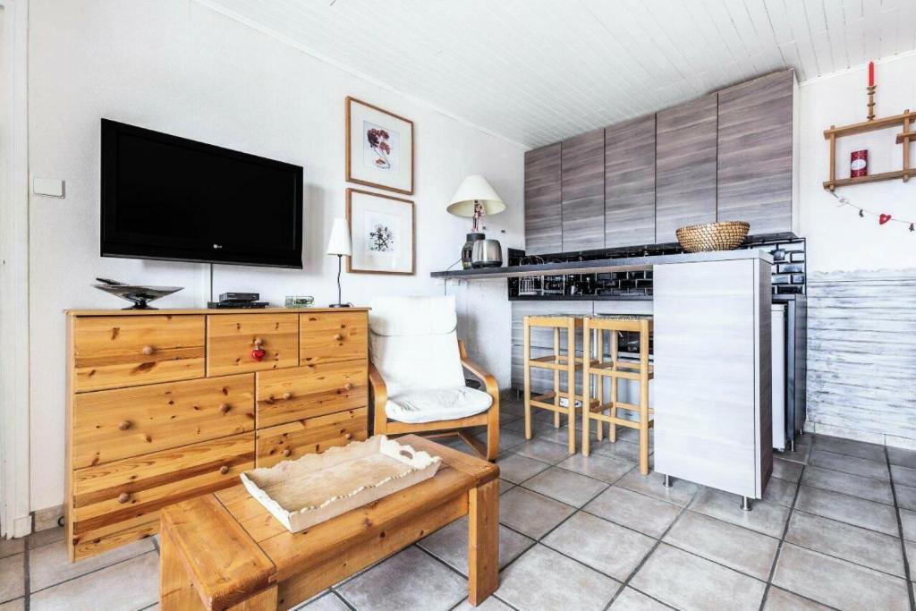 Il comprend une cuisine avec une télévision et une commode en bois. dans l'établissement Appartement à l'Alpe d'Huez retour skis aux pieds - maeva Home - Appartement skis aux pieds vue montagne 2 pièces 5 personnes - Prestige MAE-2614, à Huez