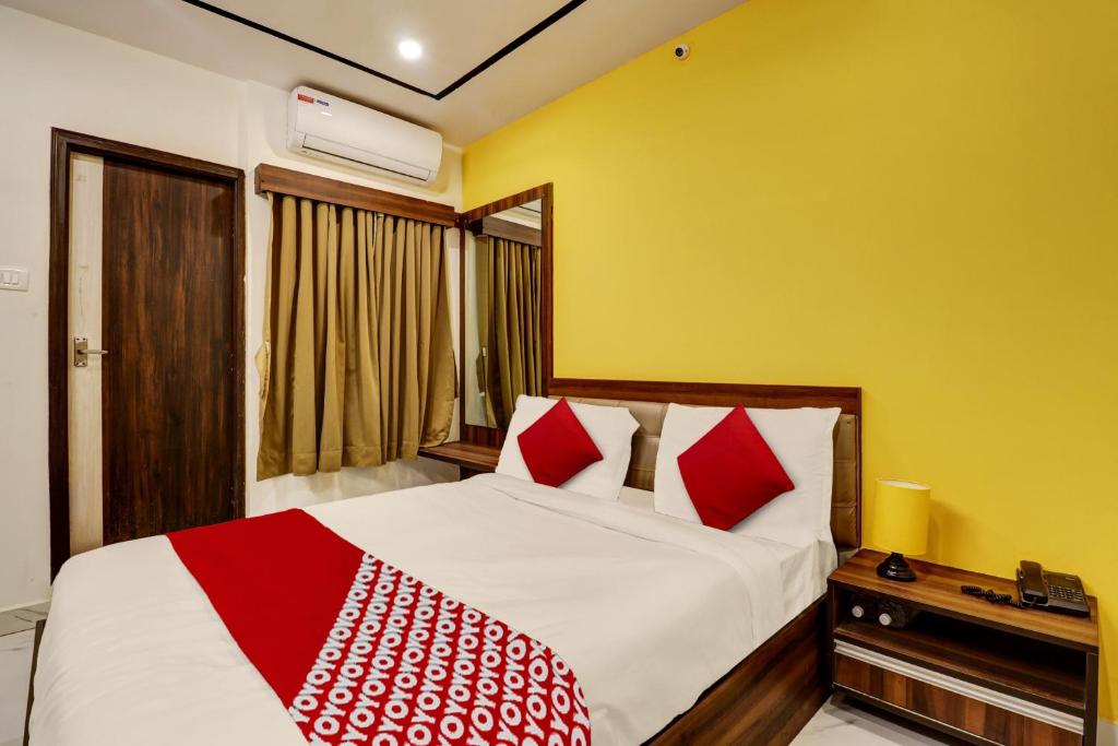 sypialnia z łóżkiem z białymi i czerwonymi poduszkami w obiekcie OYO Hotel Golden Residency w mieście Bengaluru