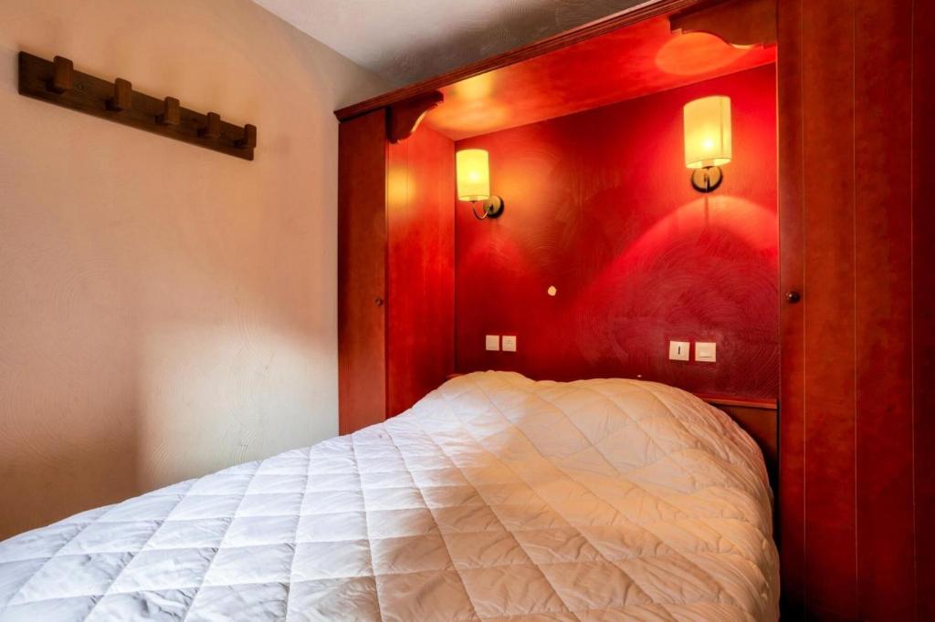 ein Schlafzimmer mit einem weißen Bett und einer roten Wand in der Unterkunft Quartier La Forêt - maeva Home - Appartement 2 pièces 5 personnes - Sélec 134 in Valmorel