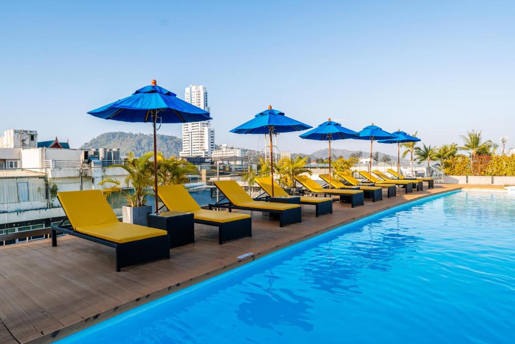 una fila de sillas y sombrillas junto a una piscina en Days Inn by Wyndham Patong Beach Phuket - SHA Extra Plus, en Patong Beach