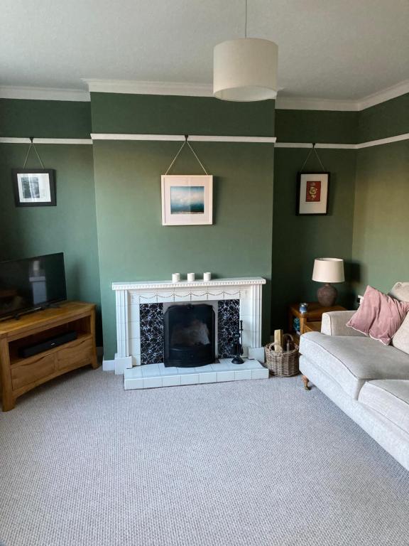 a living room with a fireplace and a couch at Cosy at Cumberland - Double room with shared bathroom in Dundonald