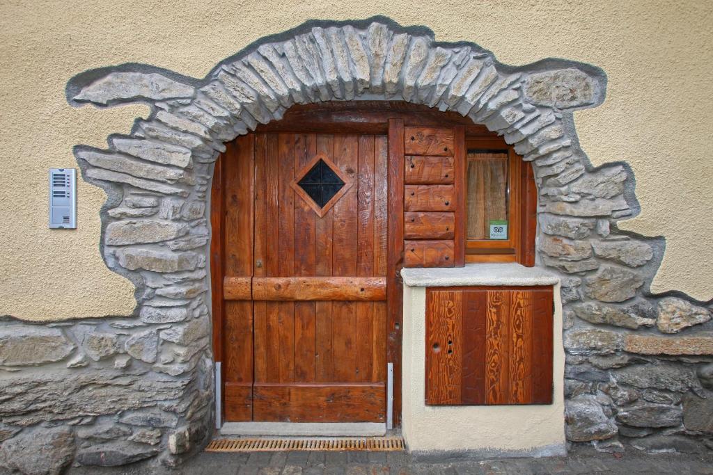 una gran puerta de madera en una pared de piedra en Casa Vacanze Elisa, en Sauze dʼOulx