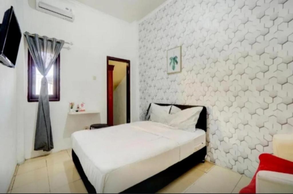 a bedroom with a bed and a white wall at RedDoorz near Plaza Araya Malang in Blimbing