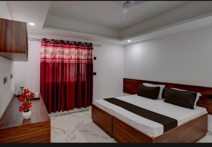 um quarto com uma cama grande e uma cortina vermelha em The Simran suites em Greater Noida