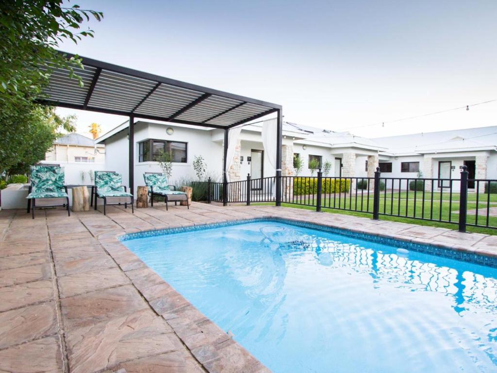 a swimming pool in a yard next to a house at Maxton Boutique Hotel Upington in Upington