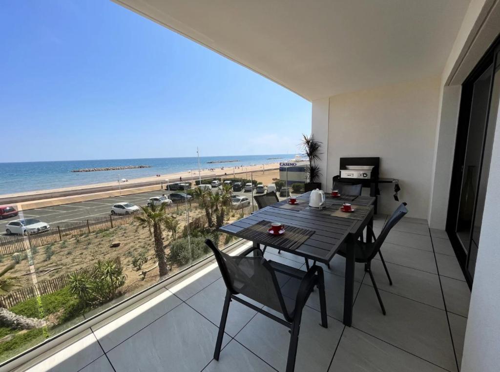 einen Tisch und Stühle auf einem Balkon mit Blick auf den Strand in der Unterkunft Splendide T2 Vue mer Valras-Plage ! in Valras-Plage
