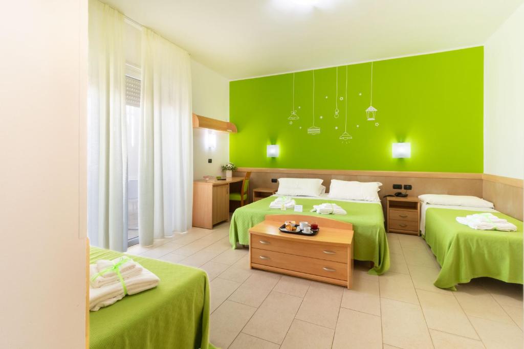 Cette chambre verte comprend 2 lits aux murs verts. dans l'établissement Marini Hotel B&B, à Lido Marini