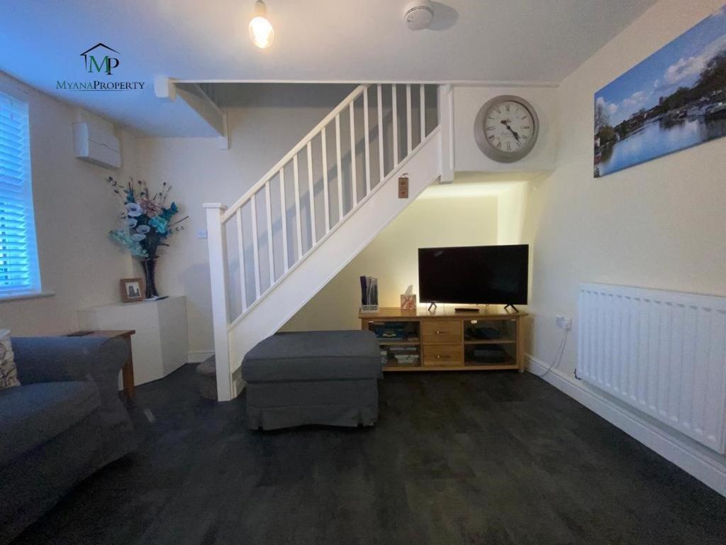 a living room with a staircase with a tv and a clock at Skippings in Beccles