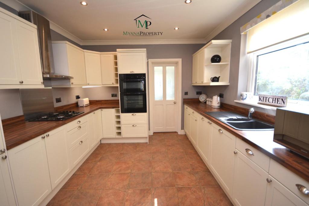 a large kitchen with white cabinets and a window at Luxurious Victorian Home by the sea - Myana House in Lowestoft