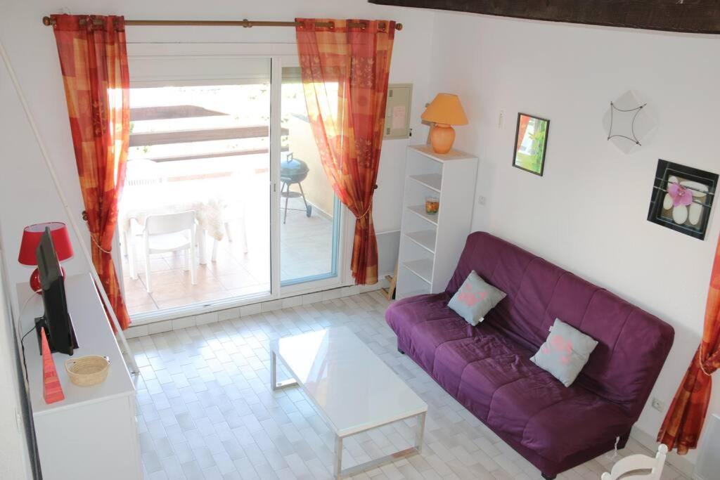 een woonkamer met een paarse bank en een tafel bij Appartement 1809 Tennis village 6 personnes in Cap d'Agde