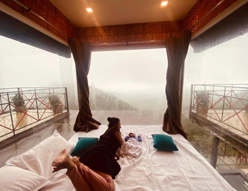 a woman laying on a bed in a room with a view at Vayalada View Point Resort in Kozhikode