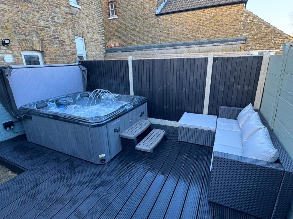 a hot tub sitting on a deck with a bench at Broadway Terrace with Hot tub in Kent