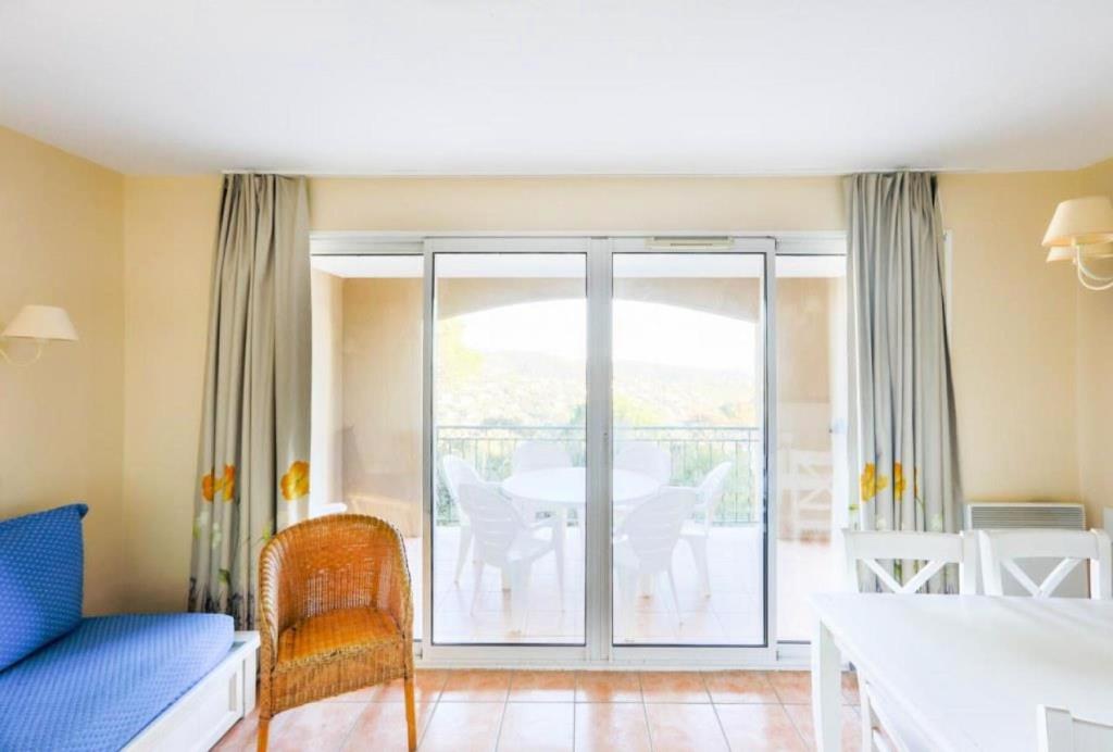 d'un salon avec un canapé et d'un balcon avec une table. dans l'établissement Résidence le Hameau des Issambres - maeva Home - 2 Pièces 6 Personnes Sélection MAE-1295, aux Issambres