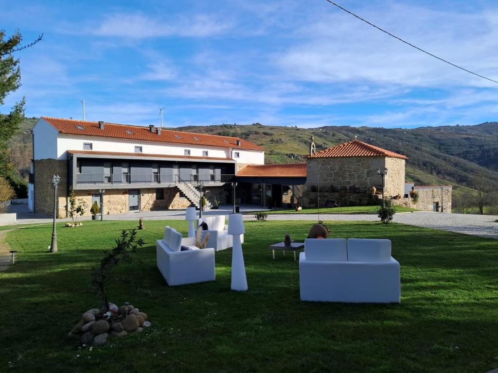 ein Gebäude mit weißen Stühlen im Gras vor einem Gebäude in der Unterkunft Alqueiturismo - Casas de Campo in Guarda