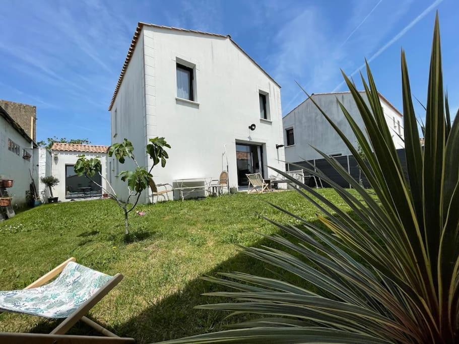 een wit huis op een grasveld met een plant bij Maison 4 chambres - 8/10 personnes, proche mer in Brem-Sur-Mer