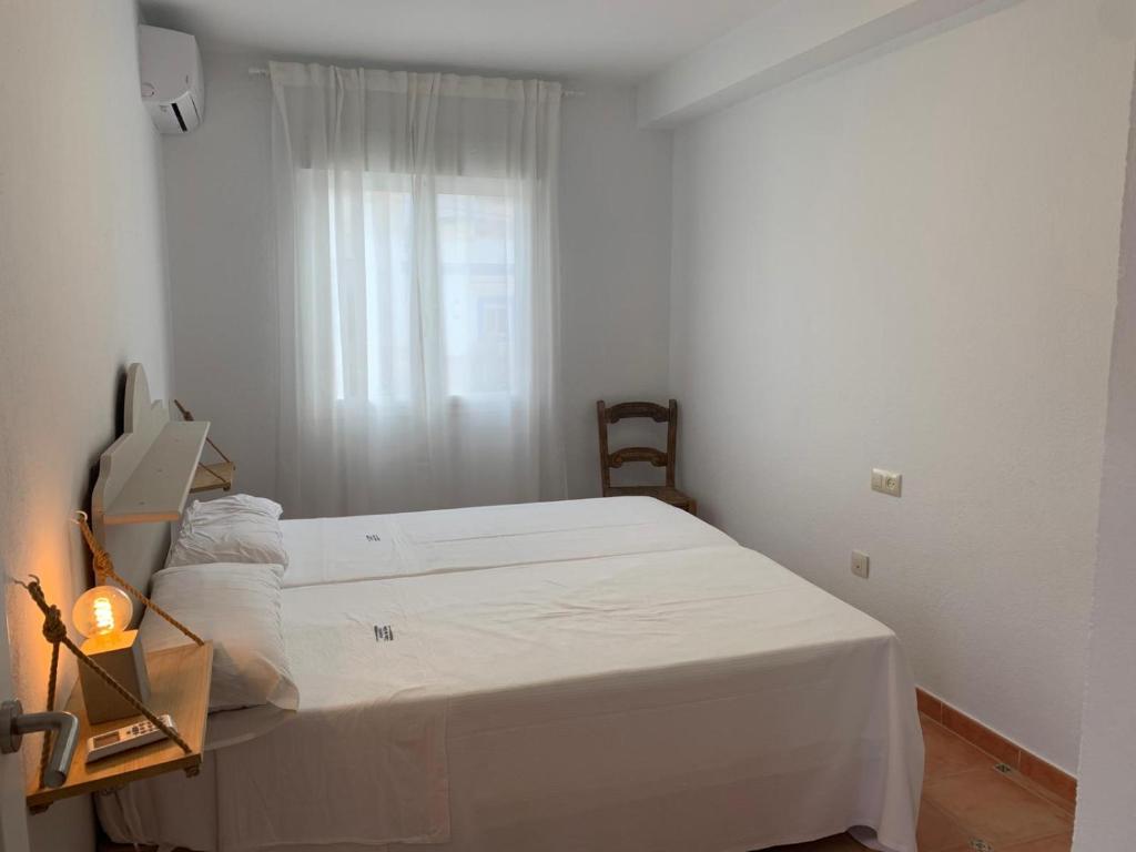 a white bedroom with a bed and a window at Cala San Pedro in El Pozo de los Frailes