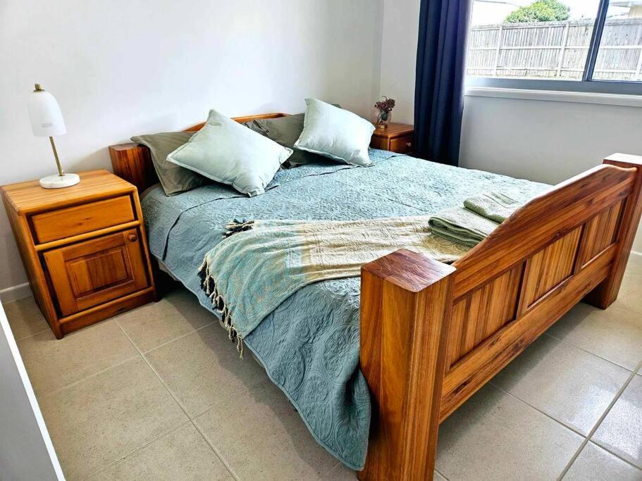 sypialnia z drewnianym łóżkiem i stolikiem nocnym w obiekcie The Ultimate Coastal Retreat w mieście Tin Can Bay