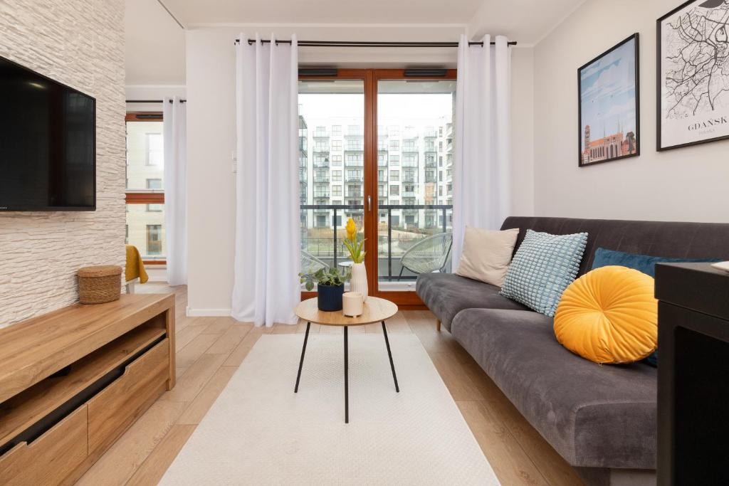 ein Wohnzimmer mit einem Sofa und einem TV in der Unterkunft Zajezdnia Wrzeszcz Modern Apartment with Balcony & Parking Gdańsk by Renters in Danzig