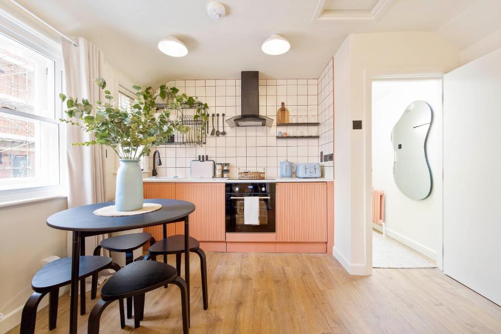 eine Küche mit einem Tisch mit Stühlen und einer Vase in der Unterkunft Cosy Studio Steps From Beach in Weymouth