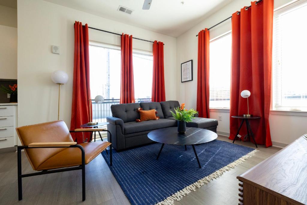 a living room with a couch and red curtains at Modern Nulu 2BR CozySuites 04 in Louisville