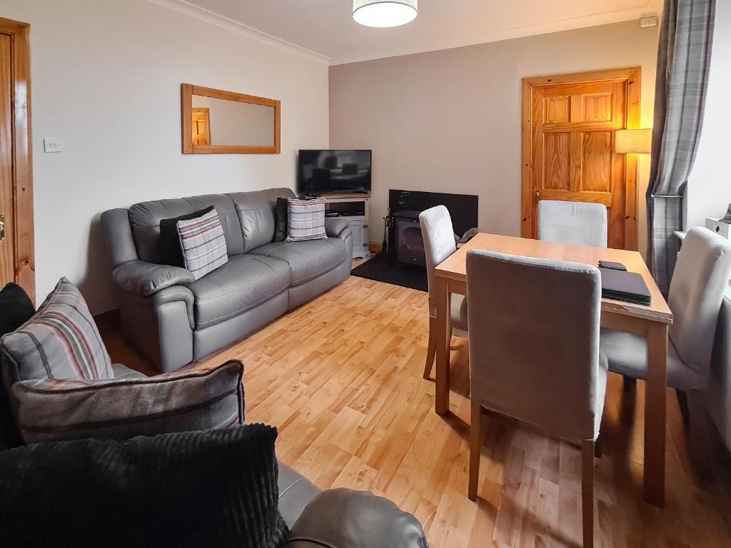 a living room with a couch and a table at Station Cottage in Trinafour