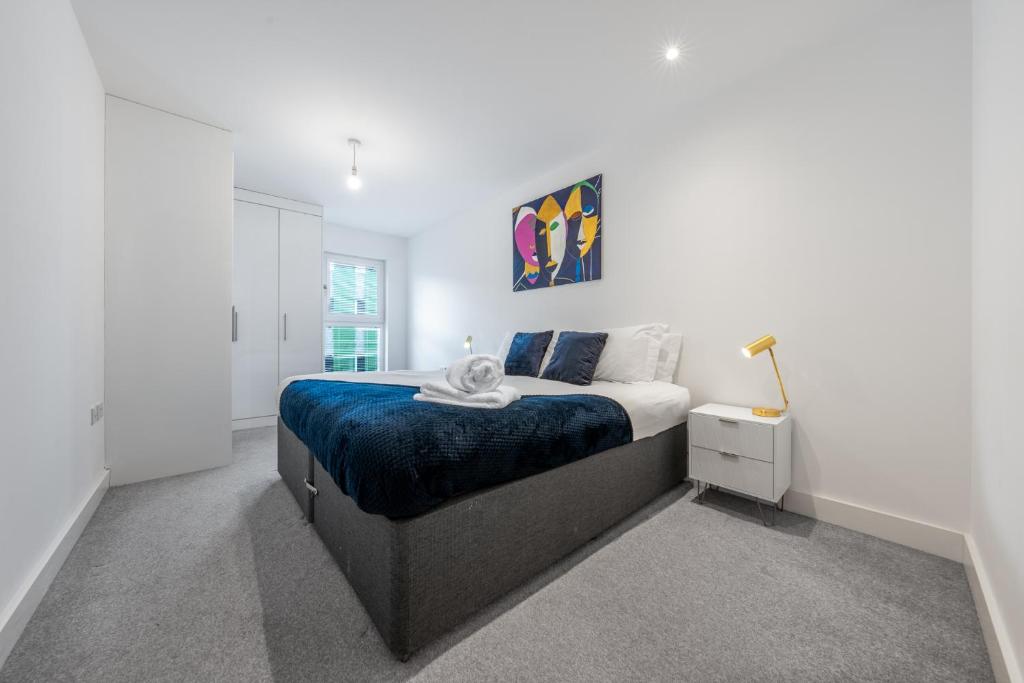 a white bedroom with a bed and a lamp at Luxury 1 Bedroom Apartment In Stevenage Town With Balcony in Stevenage