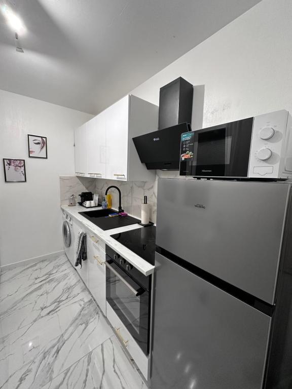 a kitchen with a refrigerator and a stove top oven at Orphea - Charming Studio Villeparisis - Proche gare / CDG / Parc des expositions in Villeparisis