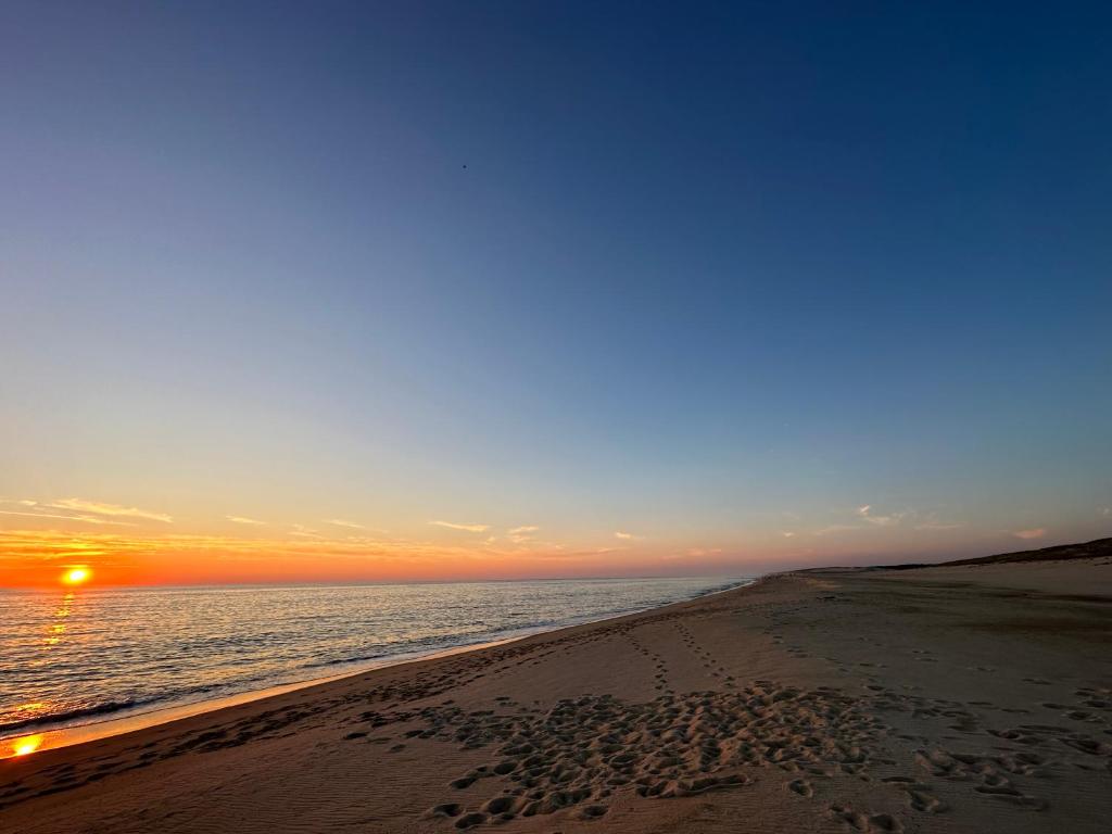 uma praia ao pôr do sol com pegadas na areia em Magnifique appart à 5 min des plages et commerces em Moliets-et-Maa