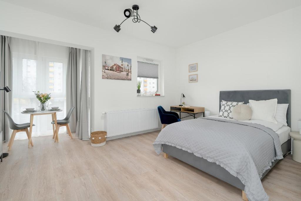 1 dormitorio blanco con 1 cama, mesa y sillas en Minimalist Studios Wojciechowskiego with Parking in Poznań by Renters en Poznan