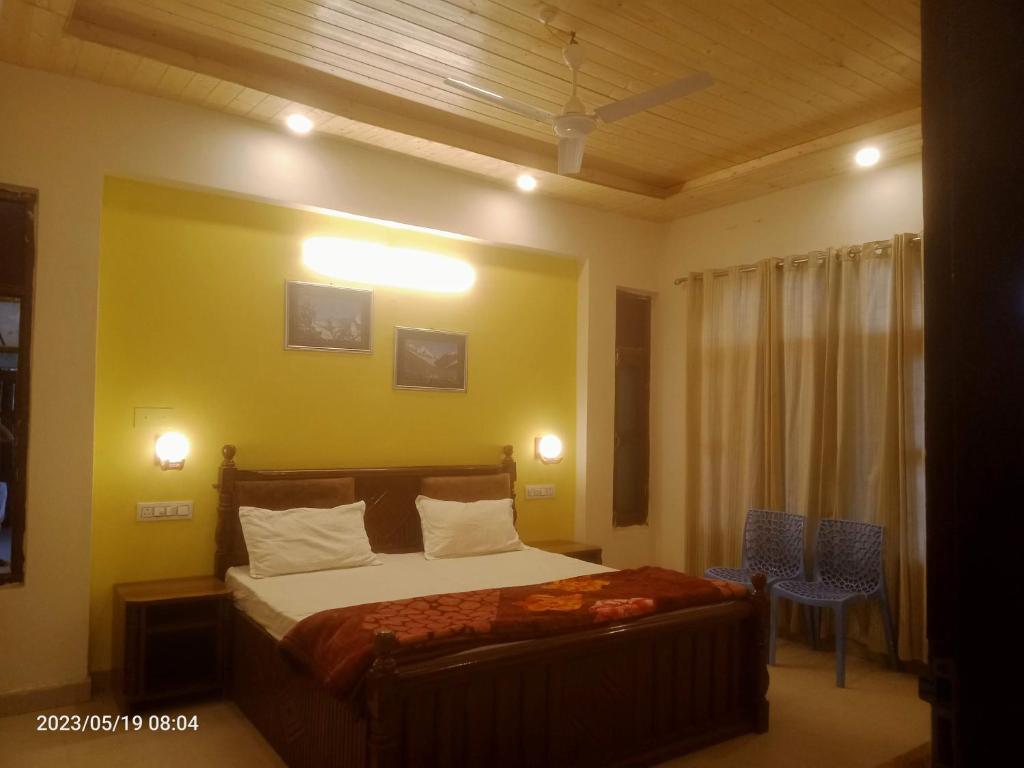 um quarto com uma cama e uma parede amarela em KAMAKSHI GUEST HOUSE em Baijnāth