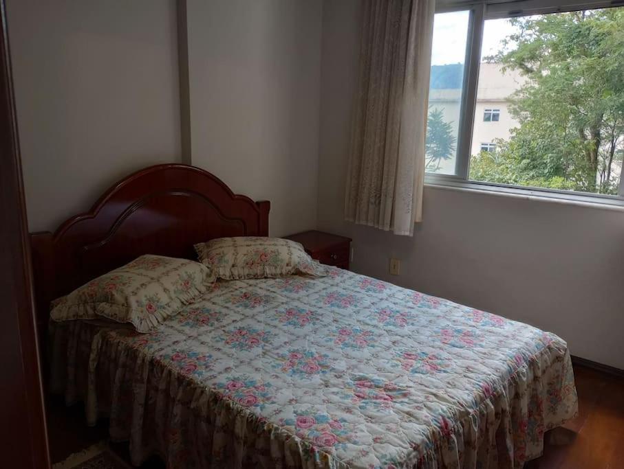 a bedroom with a bed with a quilt and a window at Apartamento in São Lourenço