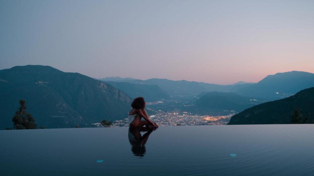 a woman sitting on the edge of a pool of water at Hotel Belvedere - Fine Dining, Hideaway & SPA in San Genesio Atesino