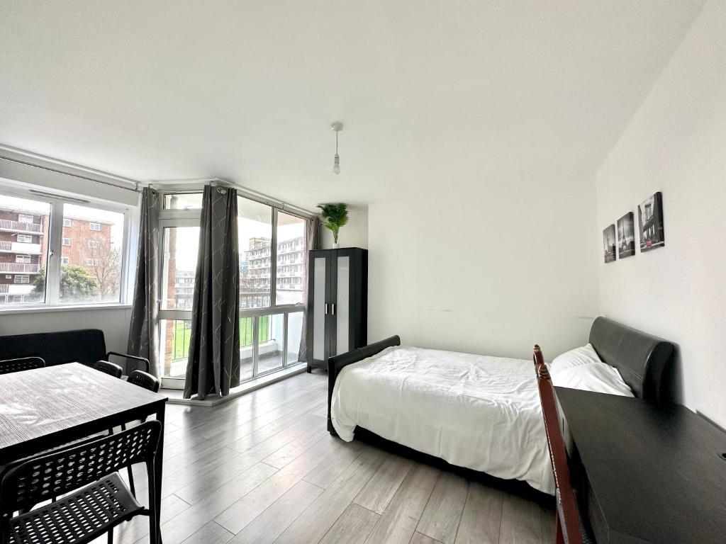 Fabulous 3 bedroom flat sleeps 6 في لندن: غرفة نوم بسرير وطاولة ونافذة