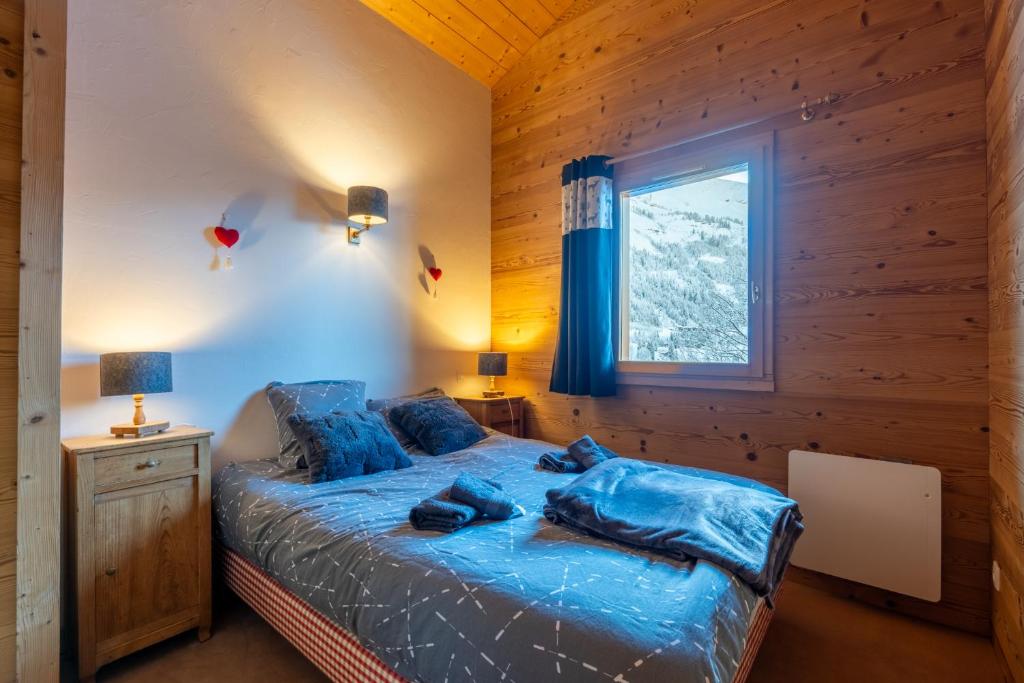 sypialnia z łóżkiem z niebieskimi prześcieradłami i oknem w obiekcie Cosymontagne - Le Chalet - 3Ch - 8 pers- Terrasse Sud, magnifique vue w mieście Clusaz
