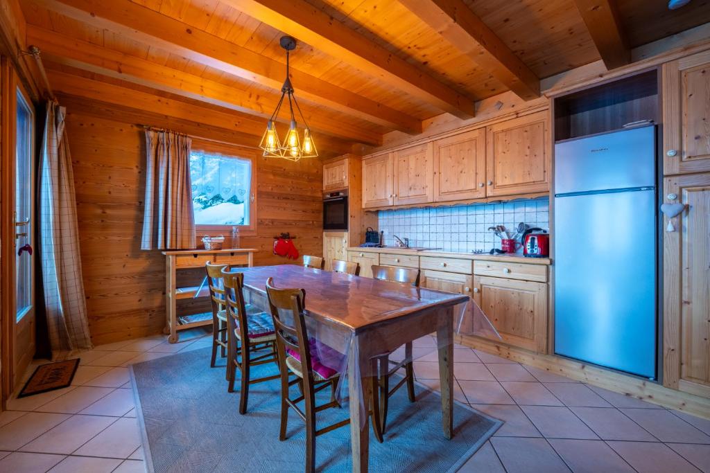 kuchnia ze stołem, krzesłami i lodówką w obiekcie Cosymontagne - Le Chalet - 3Ch - 8 pers- Terrasse Sud, magnifique vue w mieście Clusaz