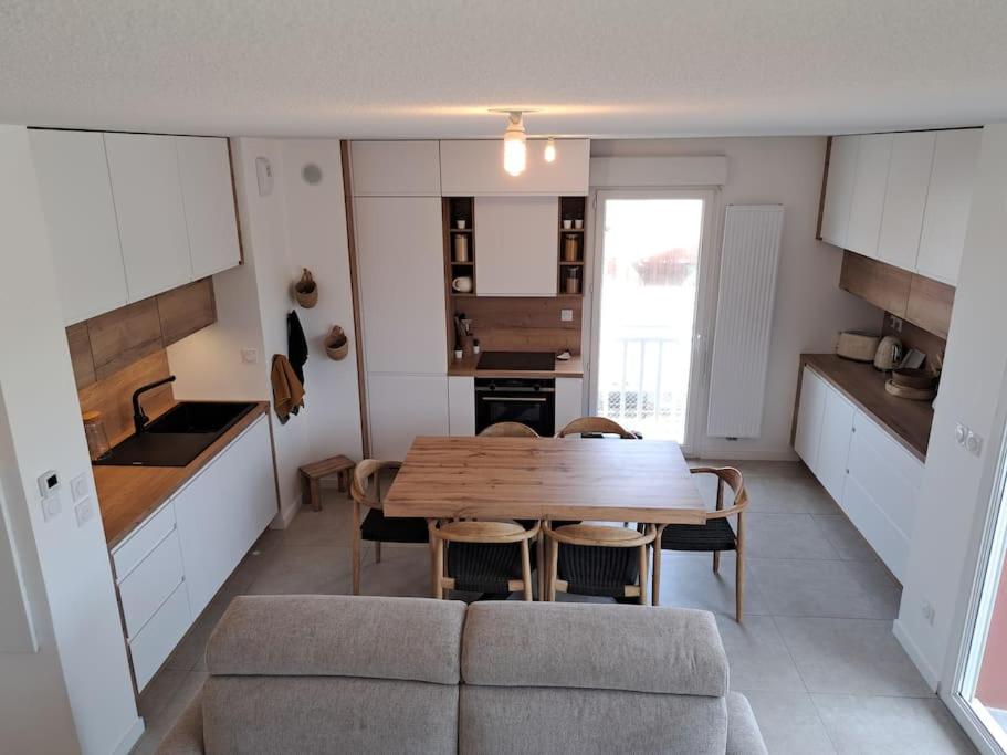 - une cuisine et une salle à manger avec une table et un canapé dans l'établissement Appartement cosy 2 chambres - 300m de la plage, à Biscarrosse