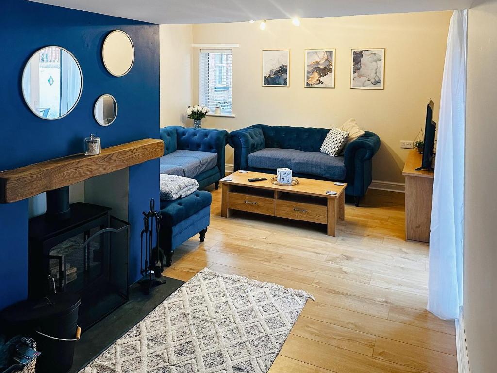 - un salon avec des canapés bleus et une cheminée dans l'établissement Mcauley Cottage, à Burgh le Marsh