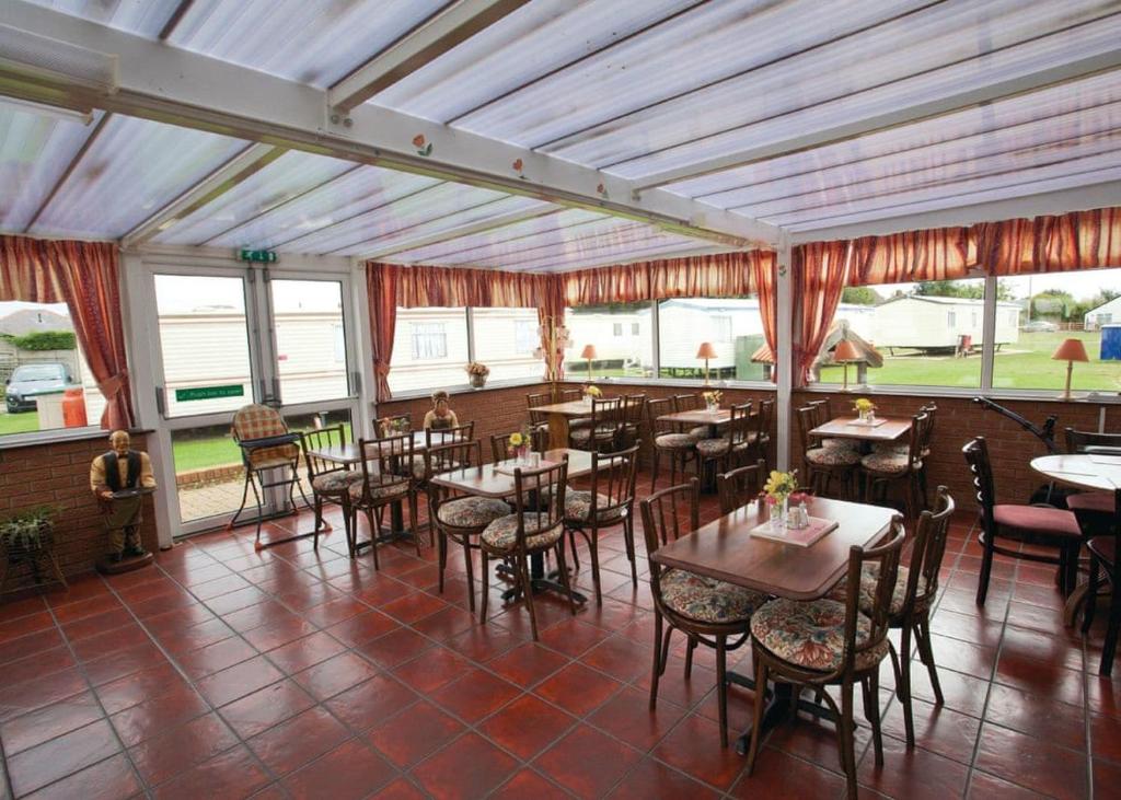 un restaurante con mesas, sillas y ventanas en Towervans Caravan Park, en Mablethorpe