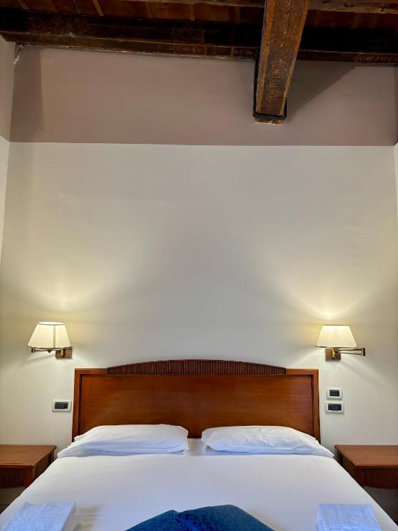 a bedroom with a bed with white sheets and two lamps at Locanda del Ghetto in Venice