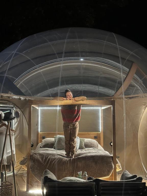 a man standing on a bed in a tent at SUITE 19 BUBBLE BY CORTIJO COLOMO in Almedinilla